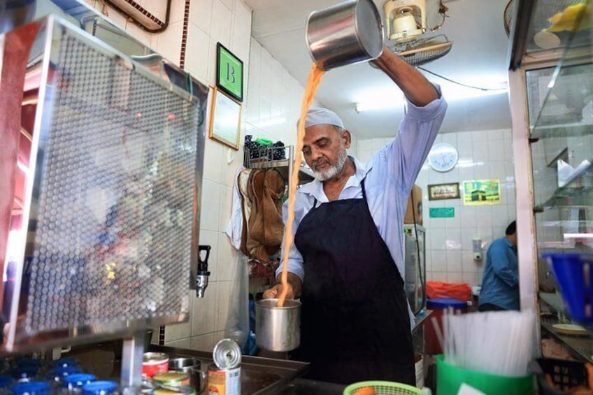 A person pouring a liquid from a container into a mesh strainer in a kitchen setting. 1