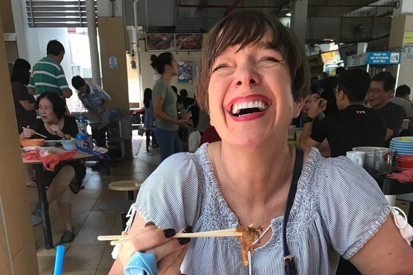 Una persona come con palillos en un ambiente interior concurrido, con mesas y otros comensales. 1
