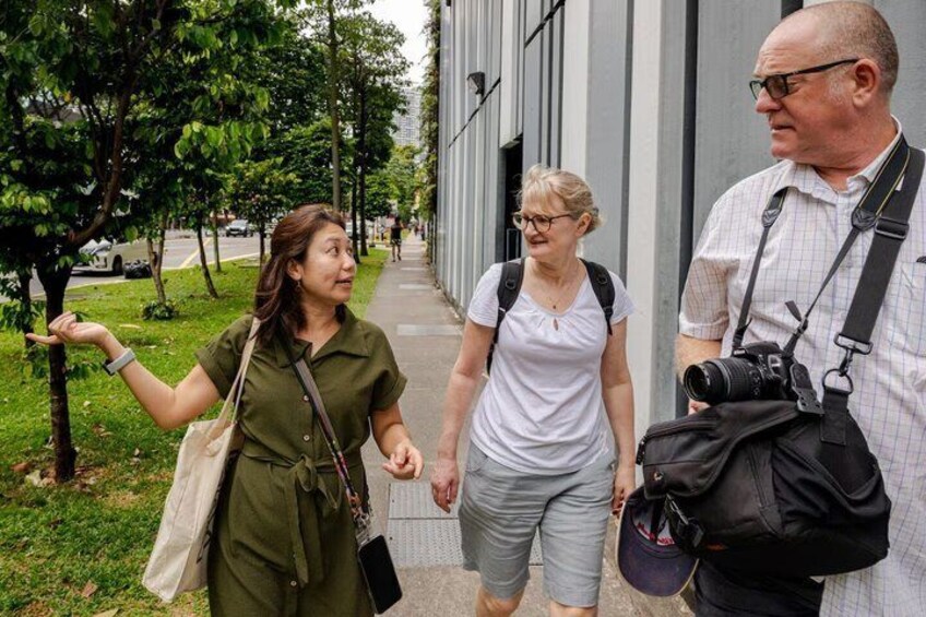 Three people walking on a sidewalk, one carrying a camera. 3