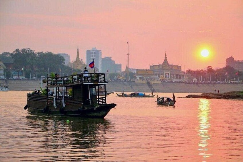 Un bateau sur une rivière, avec une vue sur la ville en arrière-plan, au coucher du soleil. 3