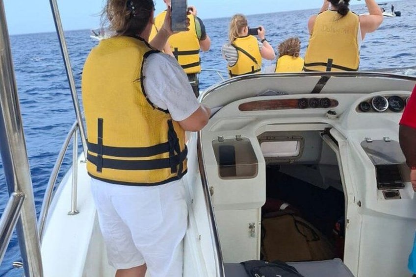 Personas en un bote usando chalecos salvavidas, con el océano al fondo. 3