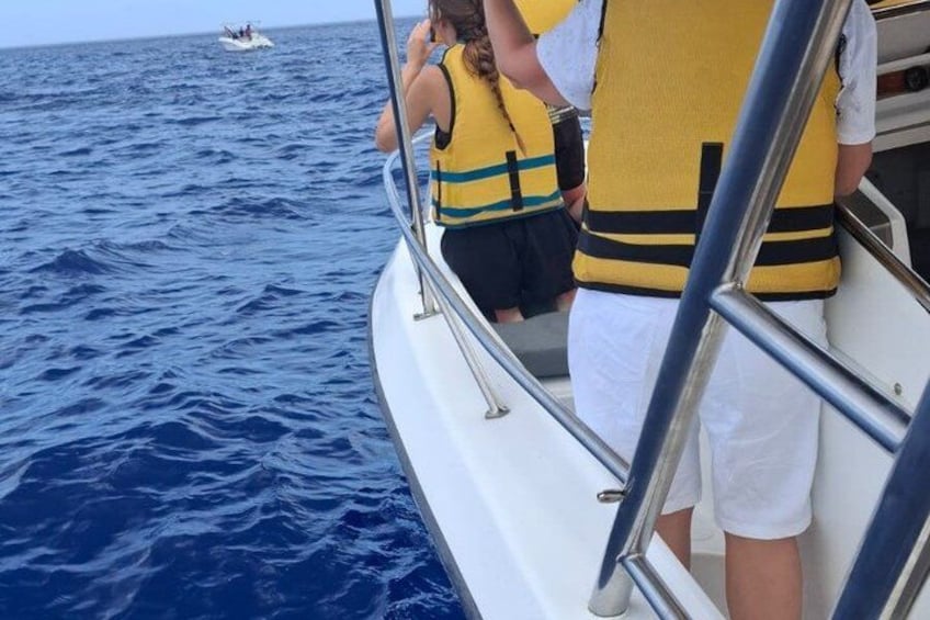 Un bateau avec des personnes portant des gilets de sauvetage, une personne prenant une photo et une autre personne observant l’eau. 5