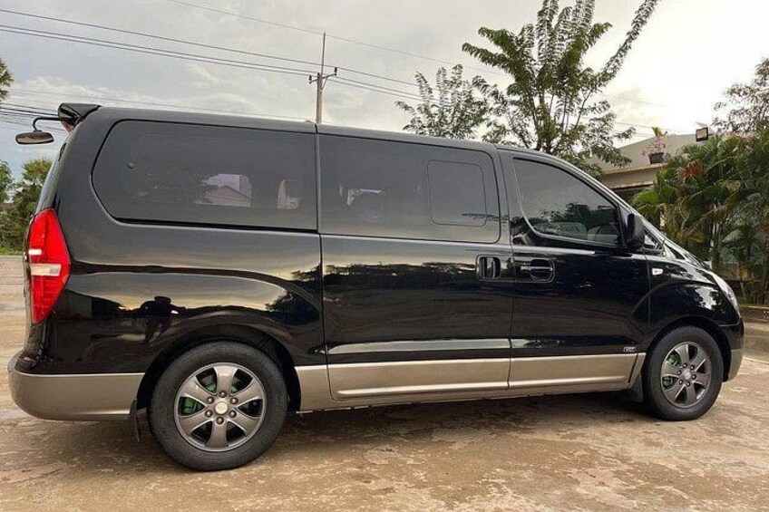 Una camioneta negra estacionada sobre una superficie de concreto, cielo despejado y algunos árboles al fondo. 1