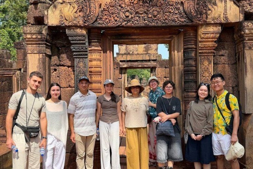 A group of people standing in front of an intricately carved stone structure. 2