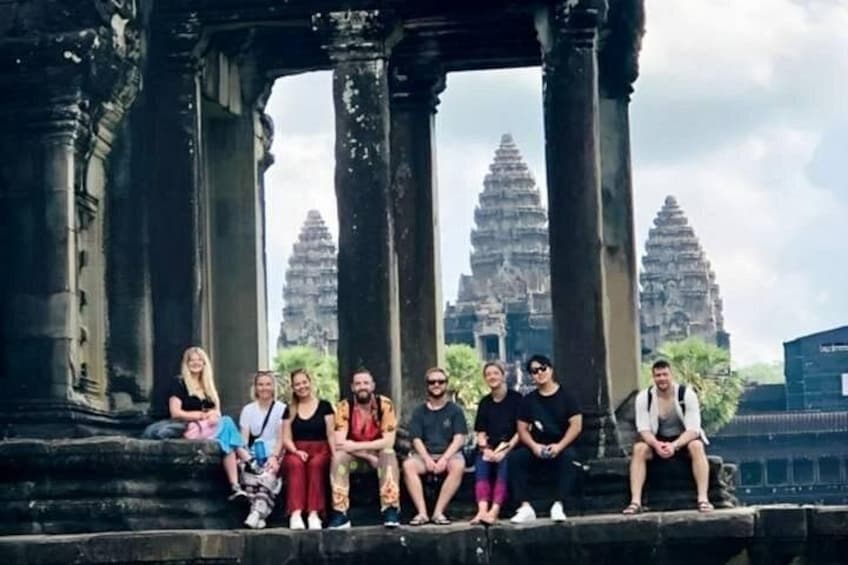 A group of people sitting on stone steps in front of ancient temple ruins. 4
