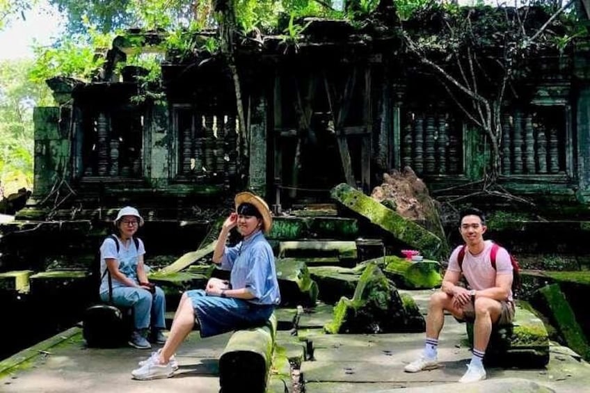 Three people sitting on stone steps in front of ancient ruins. 3
