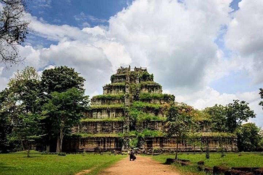A large, multi-tiered ancient temple surrounded by lush greenery and a clear sky. 4