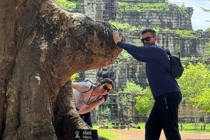 Eine Person fotografiert einen Baum vor einer historischen Struktur. 5