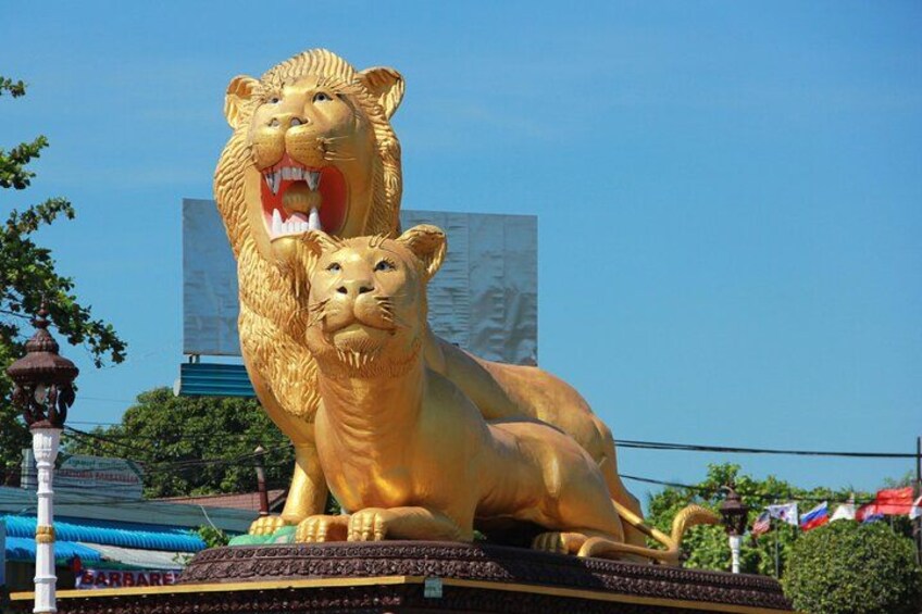 Una gran estatua dorada de león con un león más pequeño a su lado, frente a un cielo azul despejado. 4