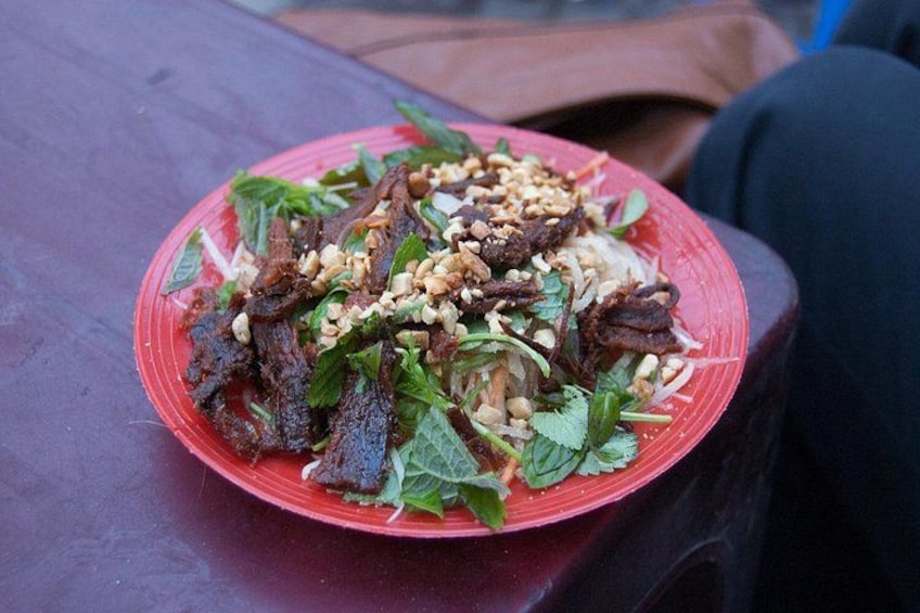 Un plato rojo con ensalada sobre una mesa de madera. 4