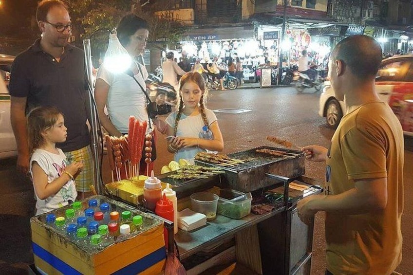 Un puesto de comida callejera con una parrilla y botellas de colores. 5