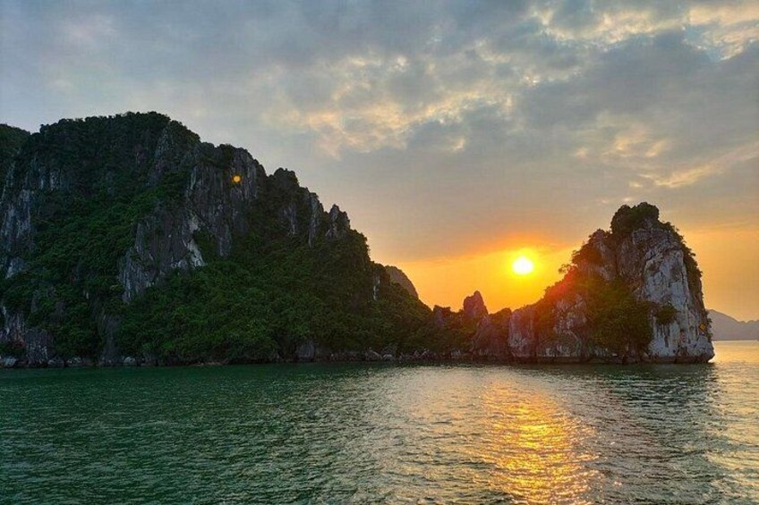 Ein Sonnenuntergang über einer Küstenlandschaft mit felsigen Klippen und ruhigem Wasser, das den Himmel spiegelt. 2