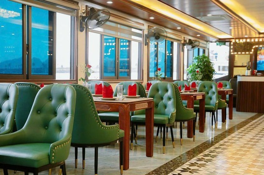 A restaurant with green upholstered chairs, wooden tables, and large windows. 5