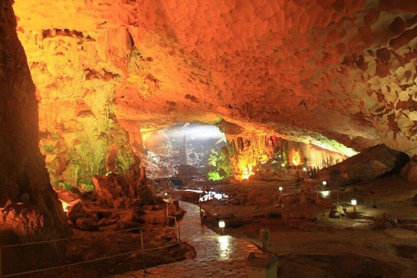 A cave with illuminated rock formations and a water stream. 2