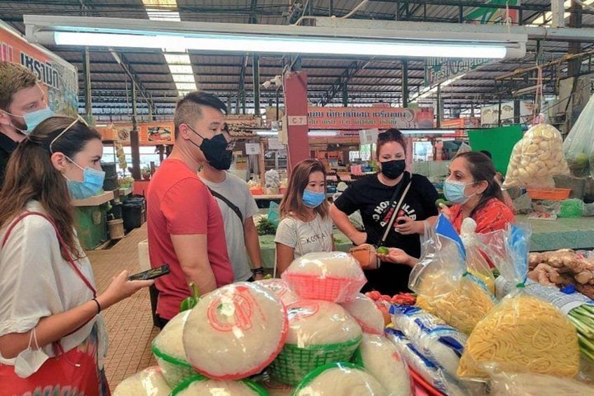 Menschen kaufen auf einem Markt ein, wo verschiedene Lebensmittel ausgestellt sind. 3