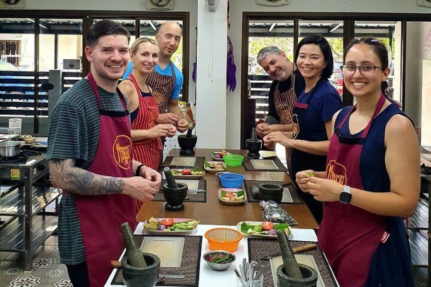 Personas con delantales preparando comida en una cocina con diferentes utensilios de cocina e ingredientes. 1
