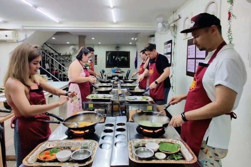 Una cocina con chefs preparando alimentos, estaciones de cocción y una mesa de buffet con platos. 3