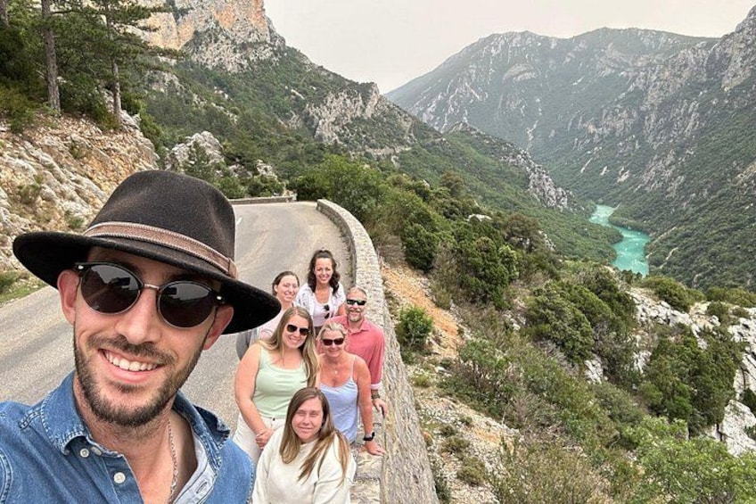 A group of people on a winding mountain road with a turquoise lake in the valley. 5