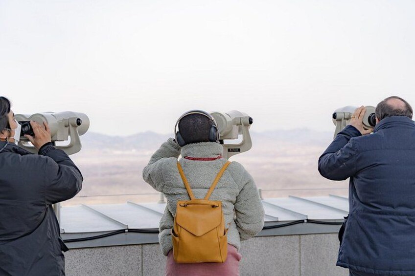 Tre persone che osservano ampi paesaggi all'orizzonte con dei telescopi. 3