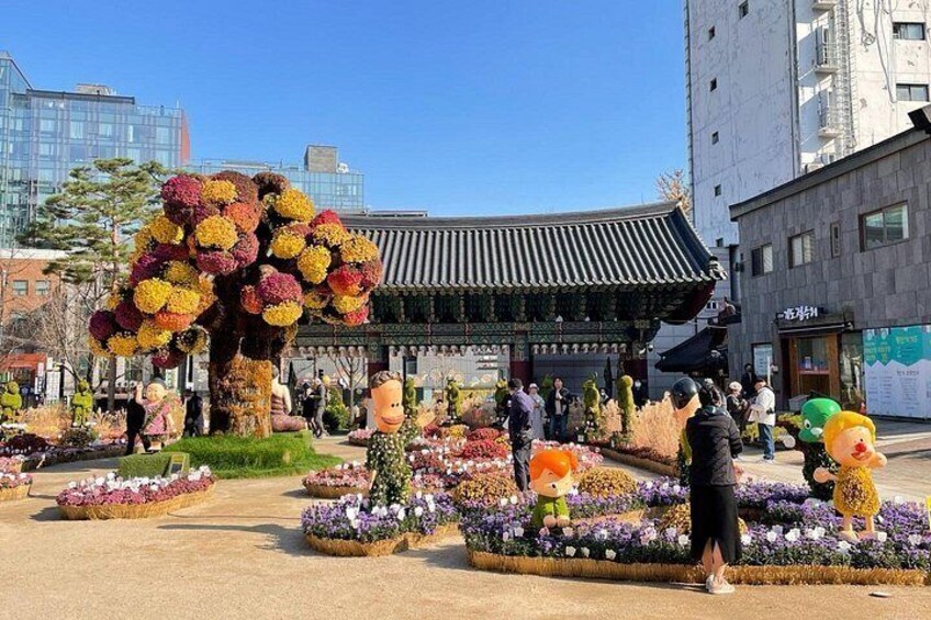 A traditional Korean building with a tiled roof, surrounded by a garden with various flowers and decorative elements. 3