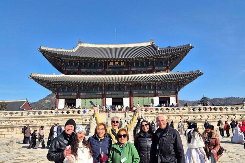 A traditional Korean building with a large audience in front. 1