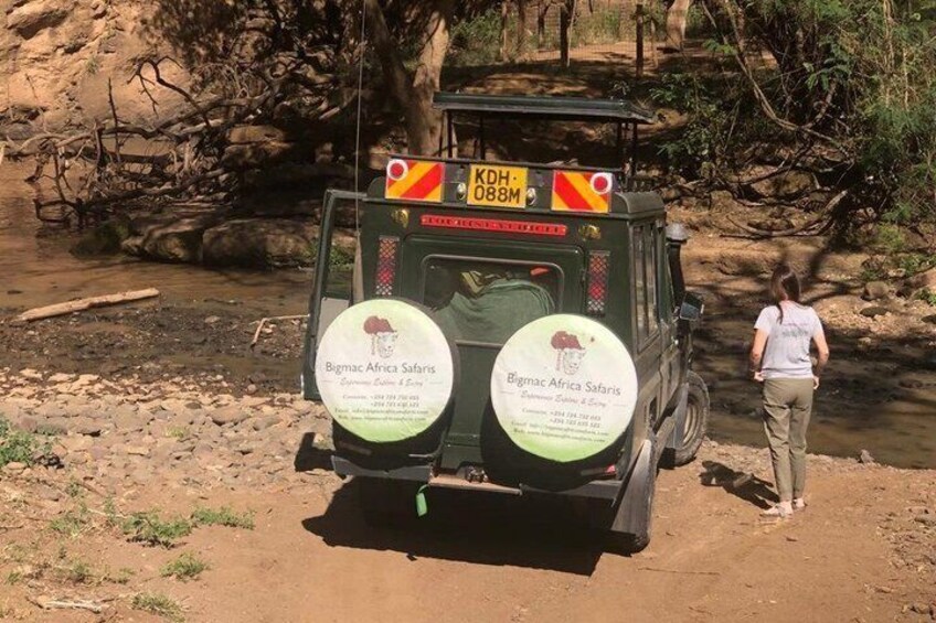 A safari vehicle with a sign reading 'Bongo Africa Safaris' parked by a river. 1
