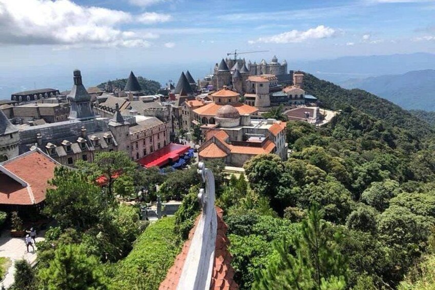 A historic town with a prominent castle, lush greenery, and a winding road. 5