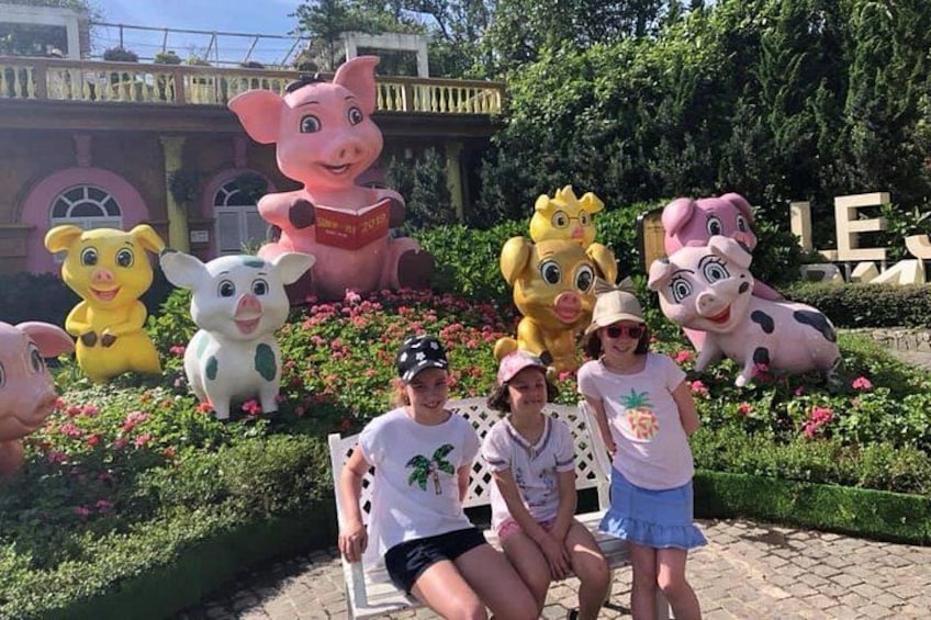 A group of people posing in front of a garden with large animal sculptures. 2