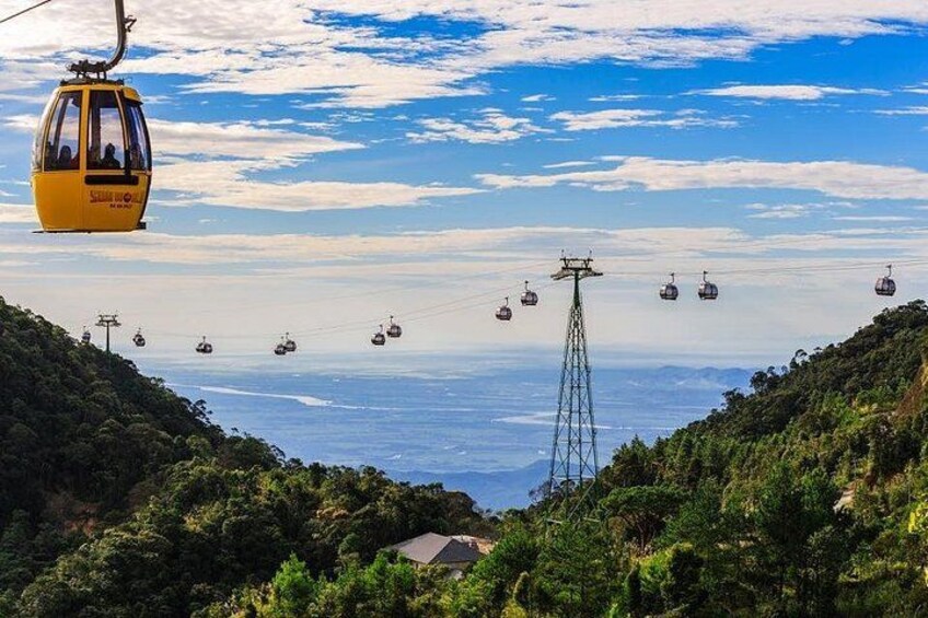 A cable car system with multiple gondolas, a mountain landscape, and a clear sky. 3