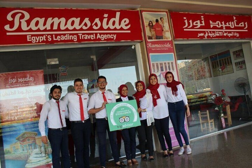 A group of people standing in front of a travel agency named Ramasside. 5