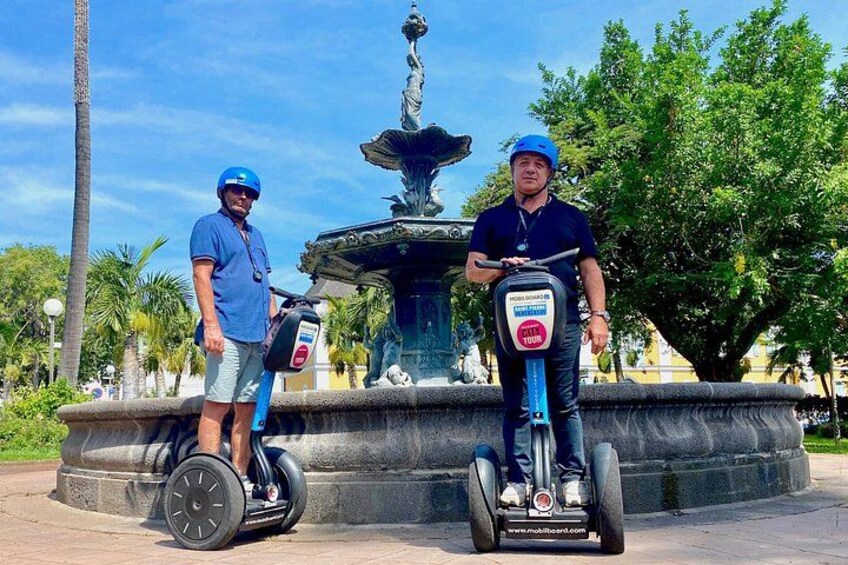 Two people on segways in front of a fountain. 4