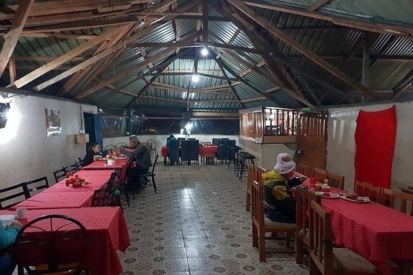 A covered dining area with tables and chairs, a high ceiling with wooden beams, and a patterned floor. 5