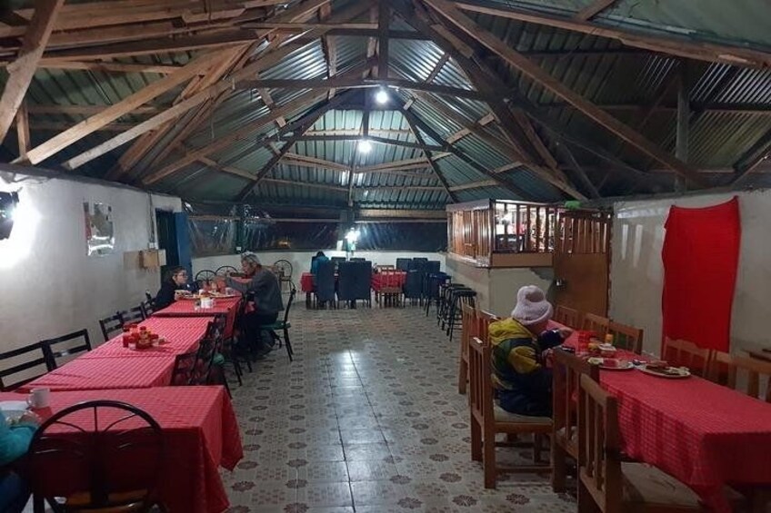 A covered dining area with tables and chairs, a high ceiling with wooden beams, and a patterned floor. 3