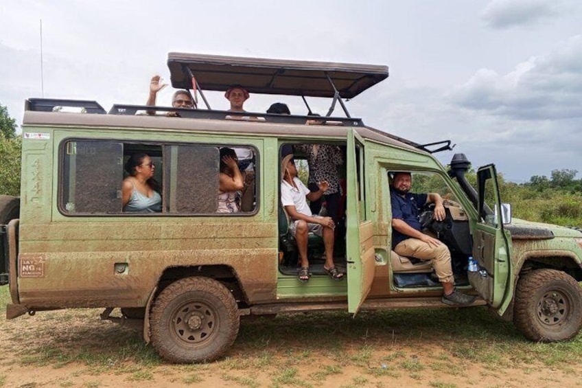 A green safari vehicle with passengers, a sunroof, and a partially open door. 5