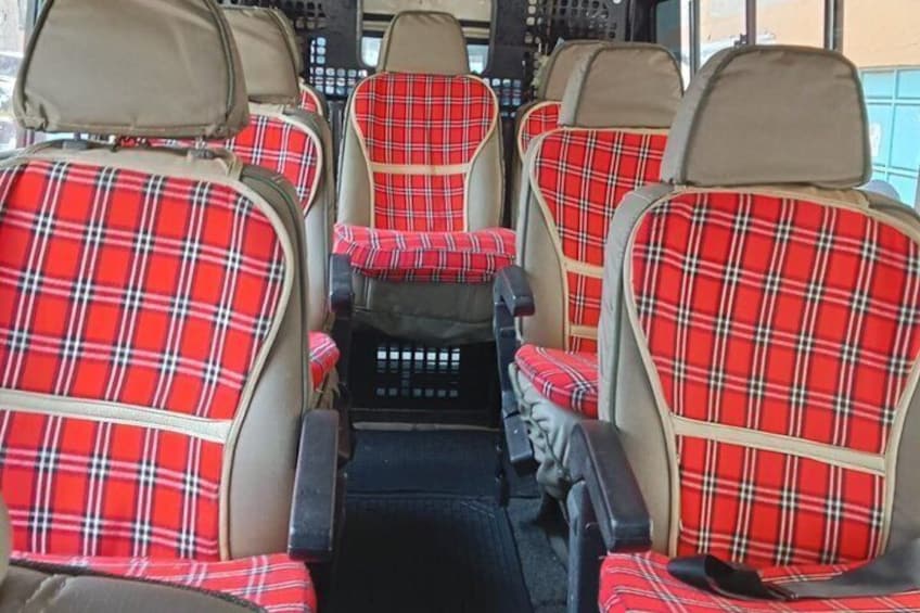 A bus interior with red plaid seats and beige headrests. 2