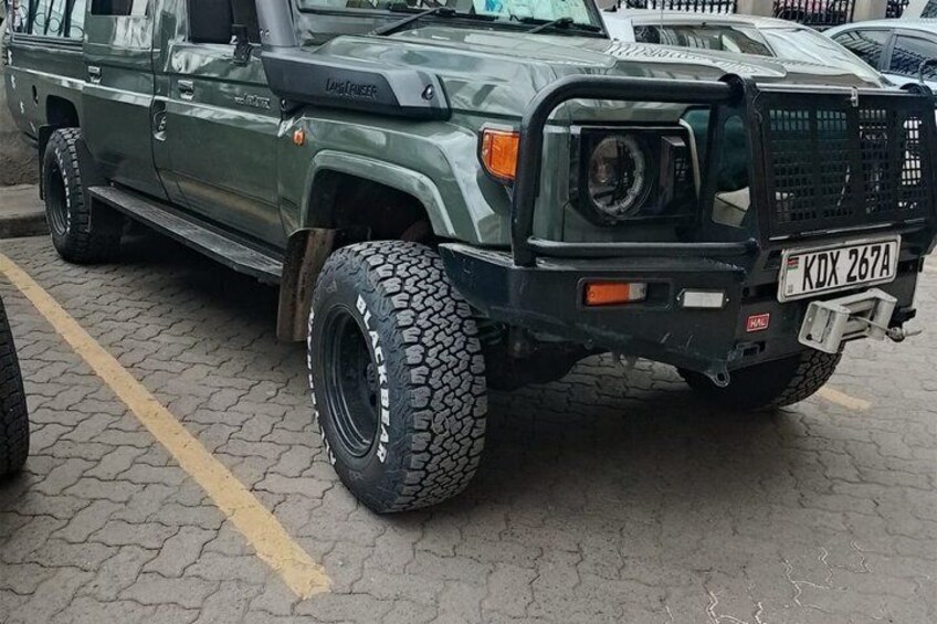 A green Hummer H3 with large off-road tires parked on a paved surface. 3