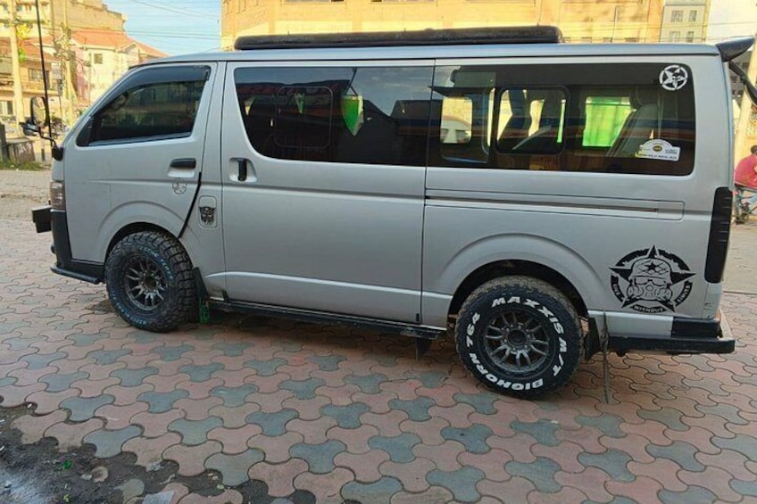 A silver van parked on a patterned pavement with a logo on the side. 2