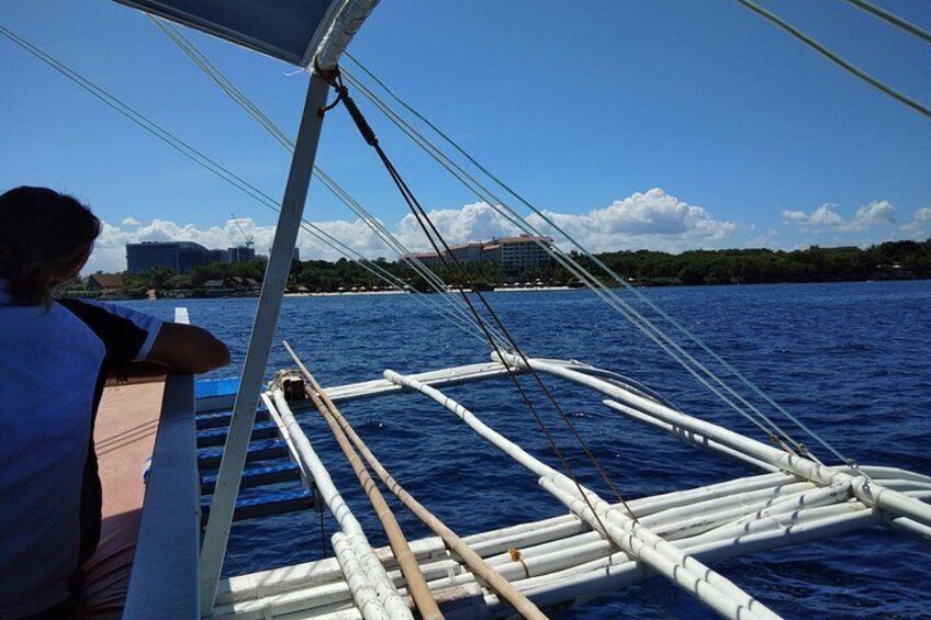 Un bote con estructura blanca y remos de madera, una persona con camisa blanca y un cielo azul despejado con nubes. 5