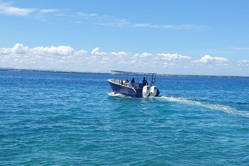 Un bote navega sobre un mar tranquilo, con cielo despejado y tierra a lo lejos en el horizonte. 3