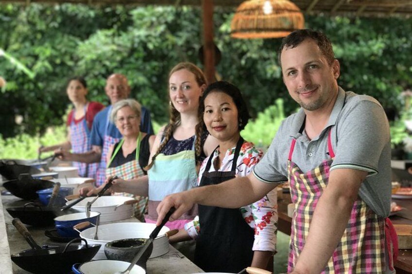 Un grupo de personas cocinando al aire libre, con utensilios de cocina e ingredientes sobre la mesa. 4