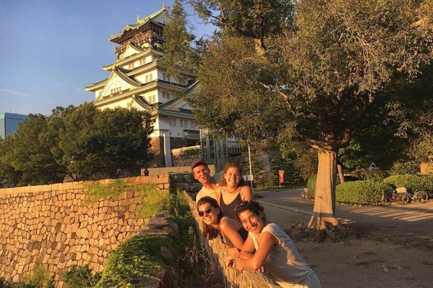 Un groupe de personnes posant près d’un mur de pierre, avec un bâtiment traditionnel japonais en arrière-plan. 4