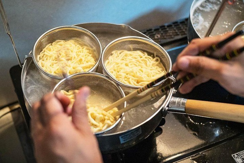 A person cooking noodles in a pan. 3