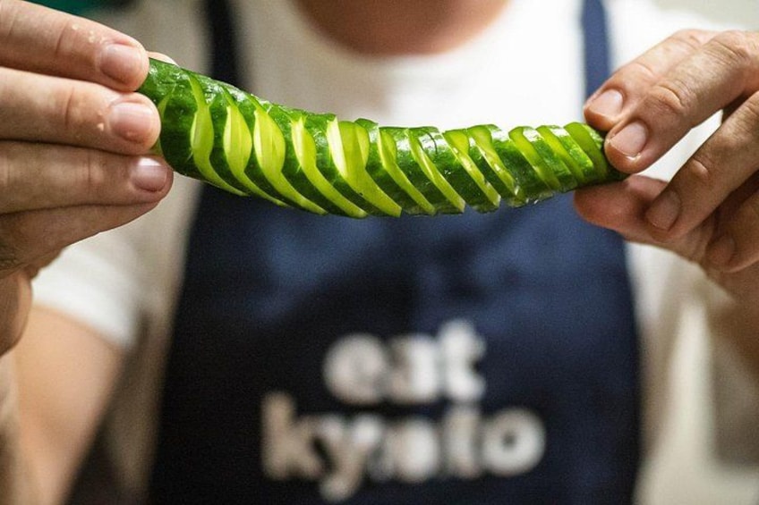 A person holding a zucchini with diagonal cuts. 4