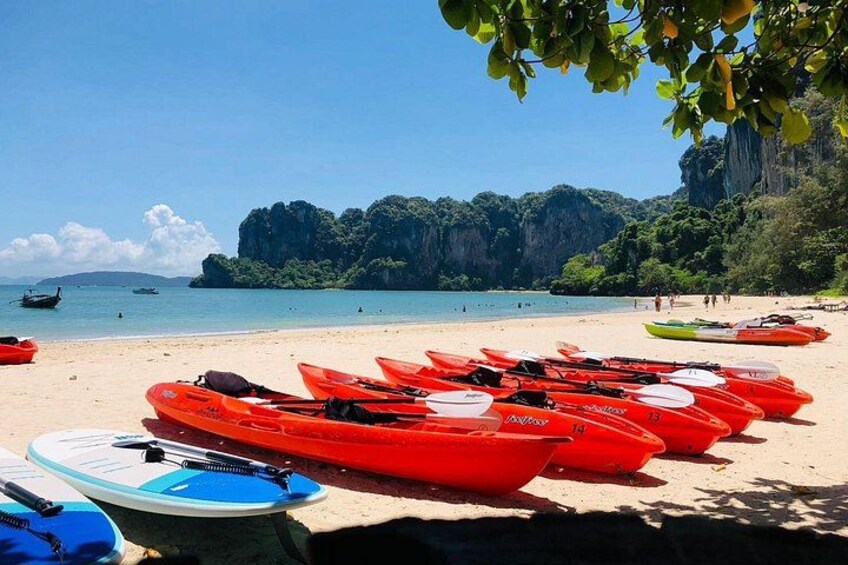 A beach with red kayaks lined up and a clear view of the sea and cliffs in the background. 2