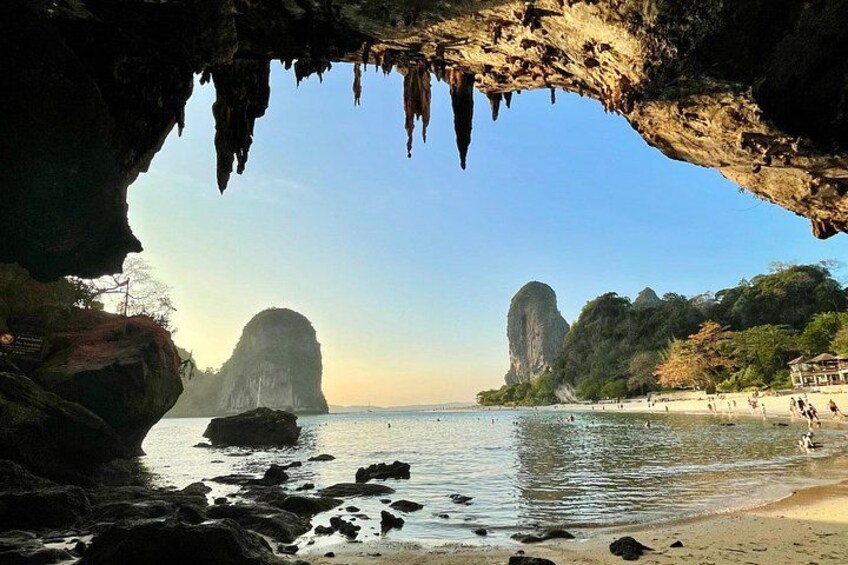 A coastal cave entrance, calm sea, and two prominent rock formations. 3
