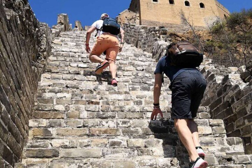 Two people climbing a stone staircase with a large building in the background. 3