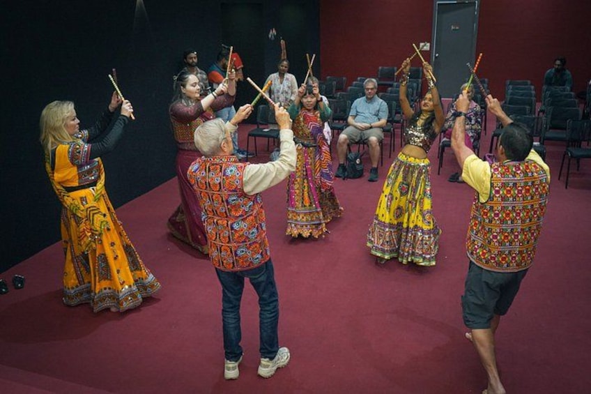 A group of people performing a traditional dance with colorful costumes and sticks. 3