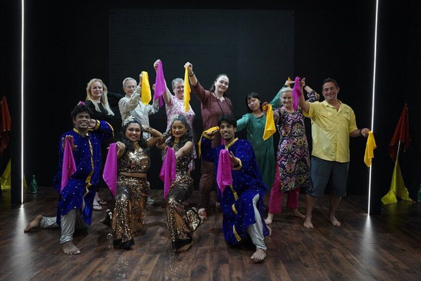 A group of people in colorful costumes on a stage with a dark background. 4