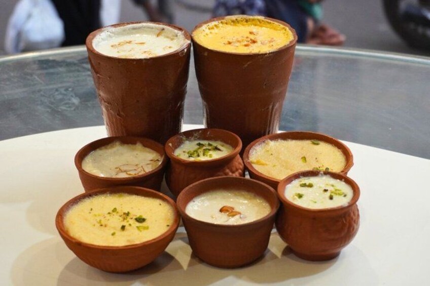 A variety of desserts in clay cups, some with nuts on top. 3