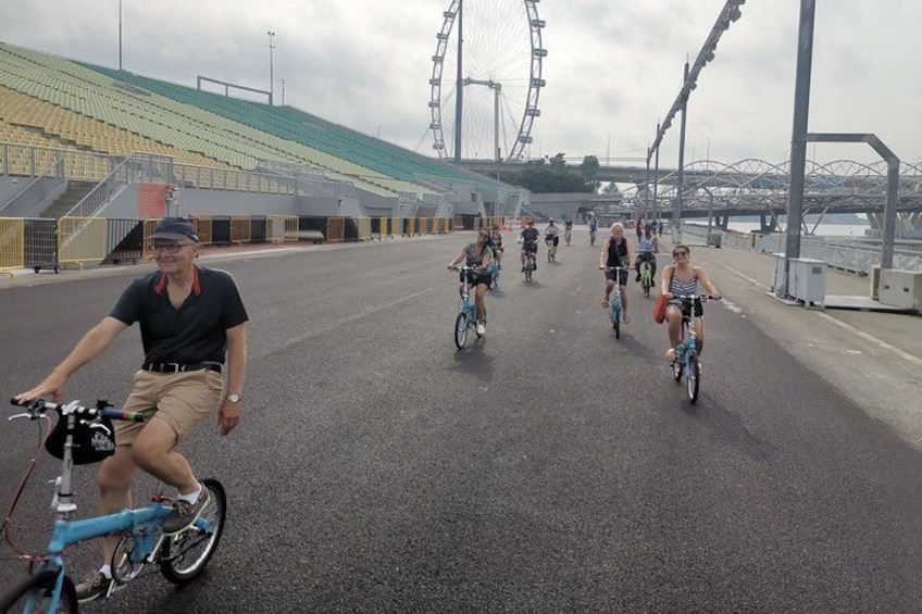 A group of cyclists on a bridge with a large Ferris wheel in the background. 4